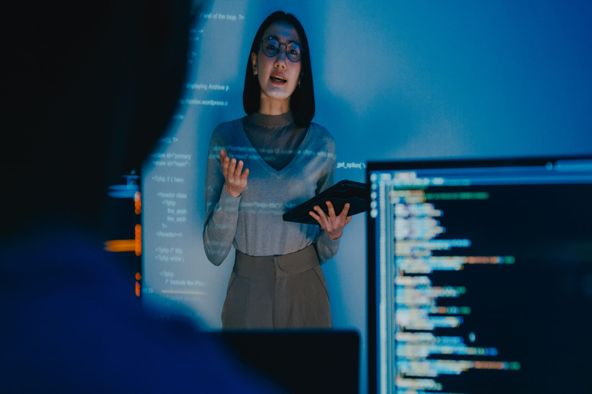 Woman presenting in front of a projected code screen