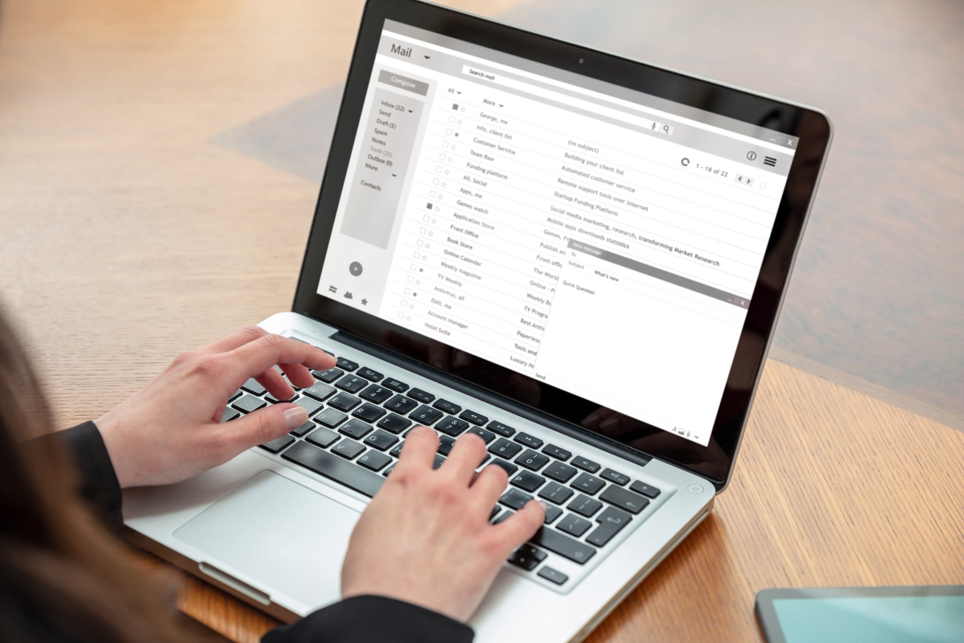 Close-up of hands using a laptop with email inbox displayed on screen.