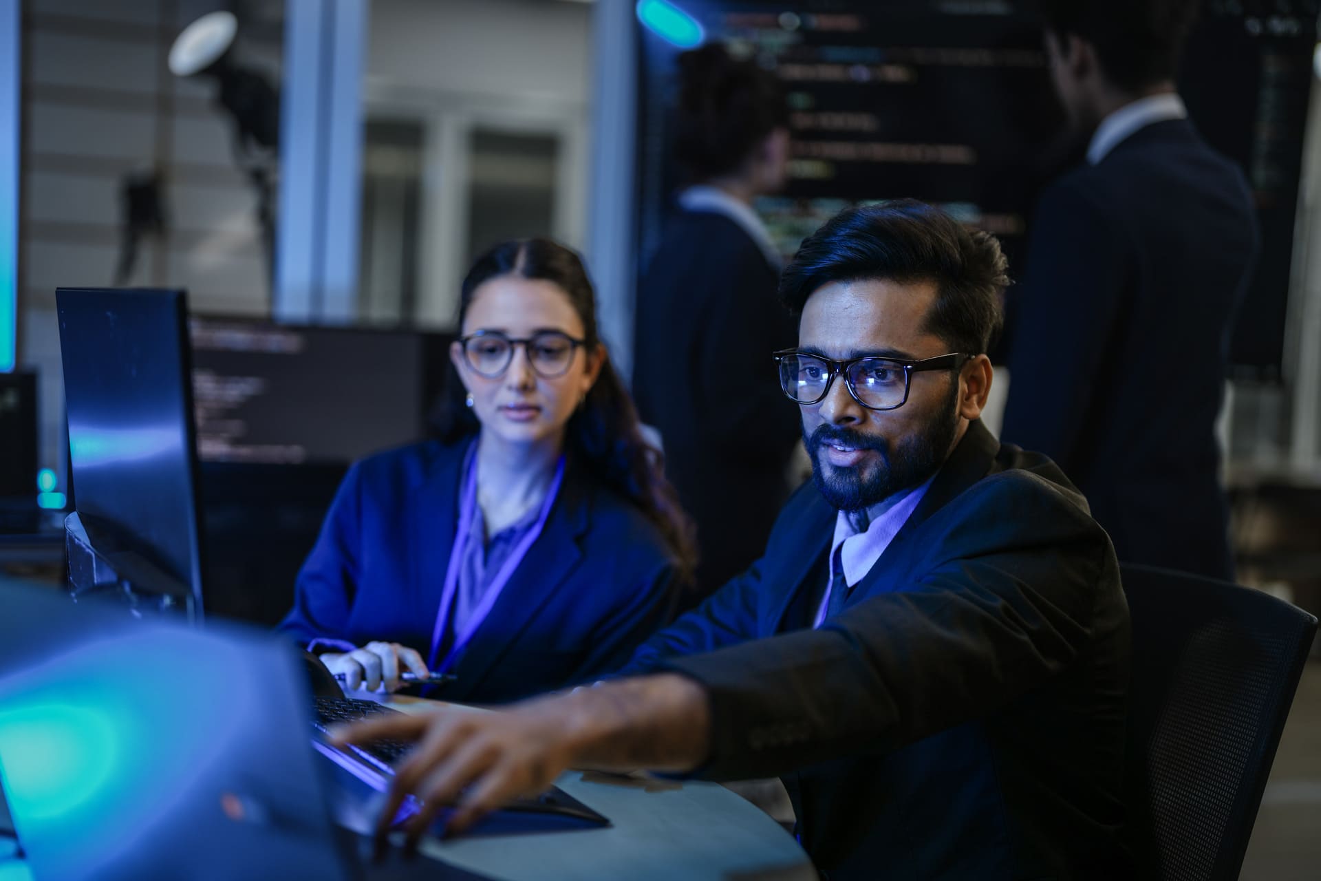 Cybersecurity team collaborating in a dark monitoring room
