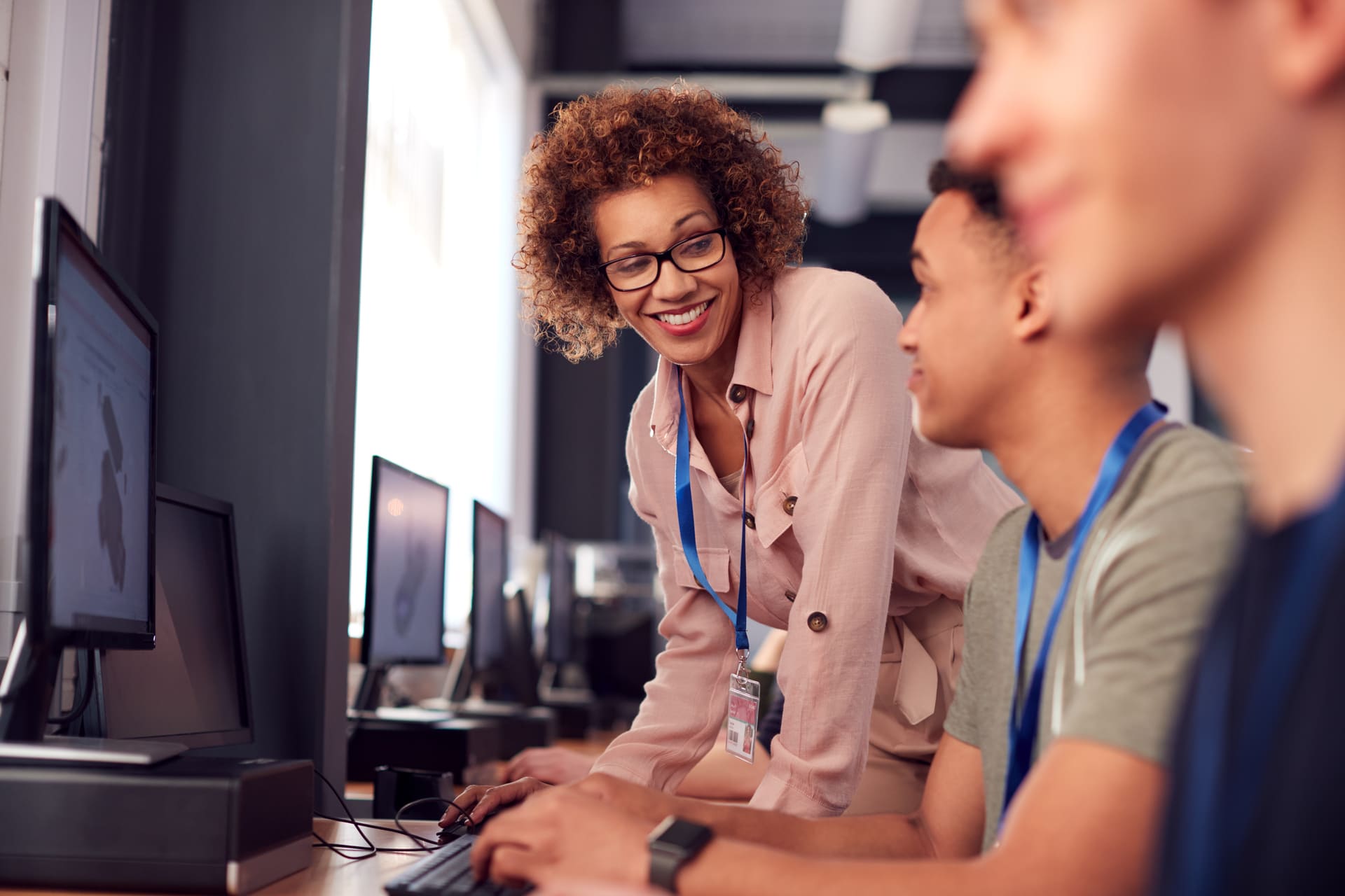Female tutor helping students with computer-related tasks in a lab