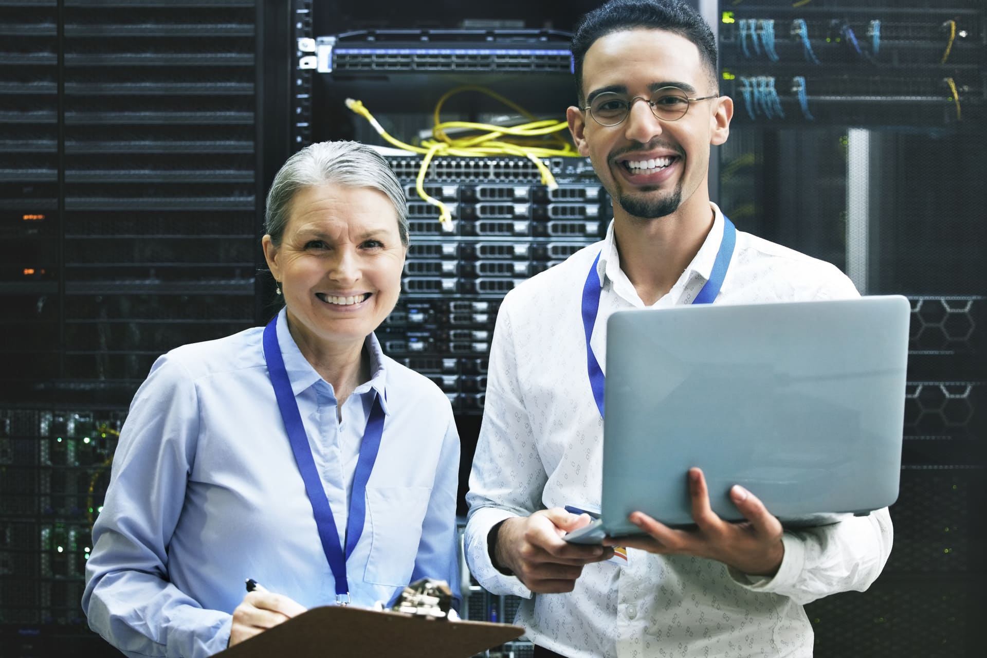 Two IT specialists smiling while working in a server room