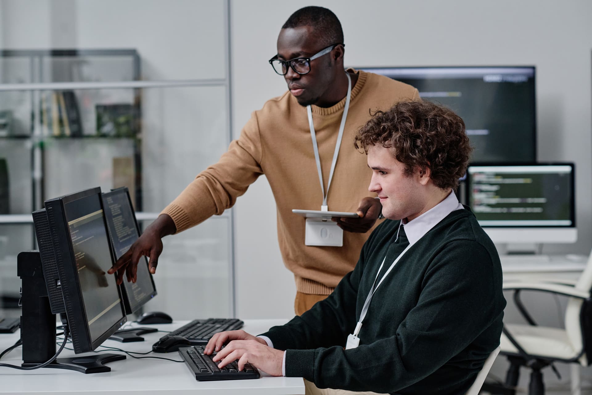Two developers discussing code on a computer screen