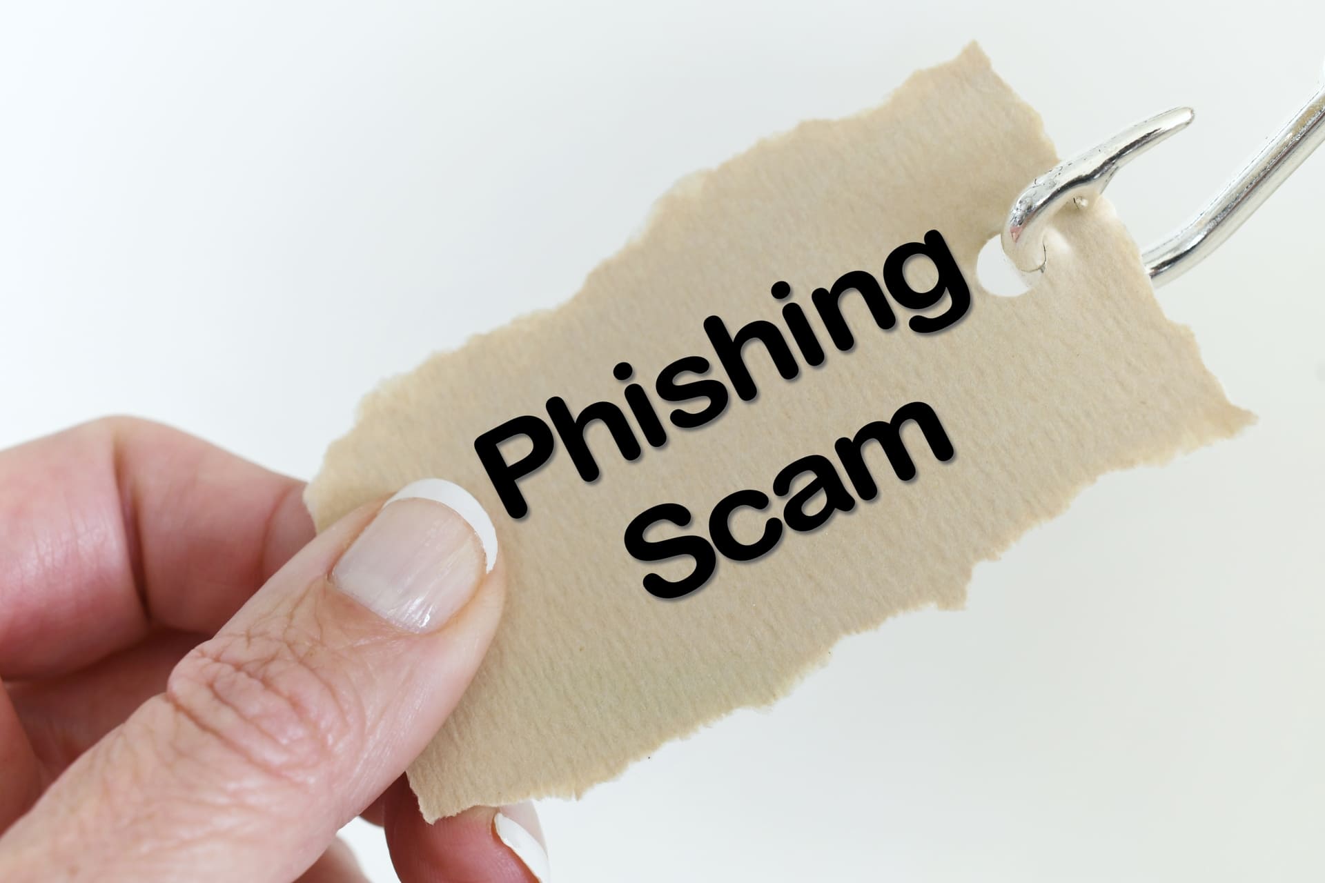 fingers hold paper with phising scam words on it