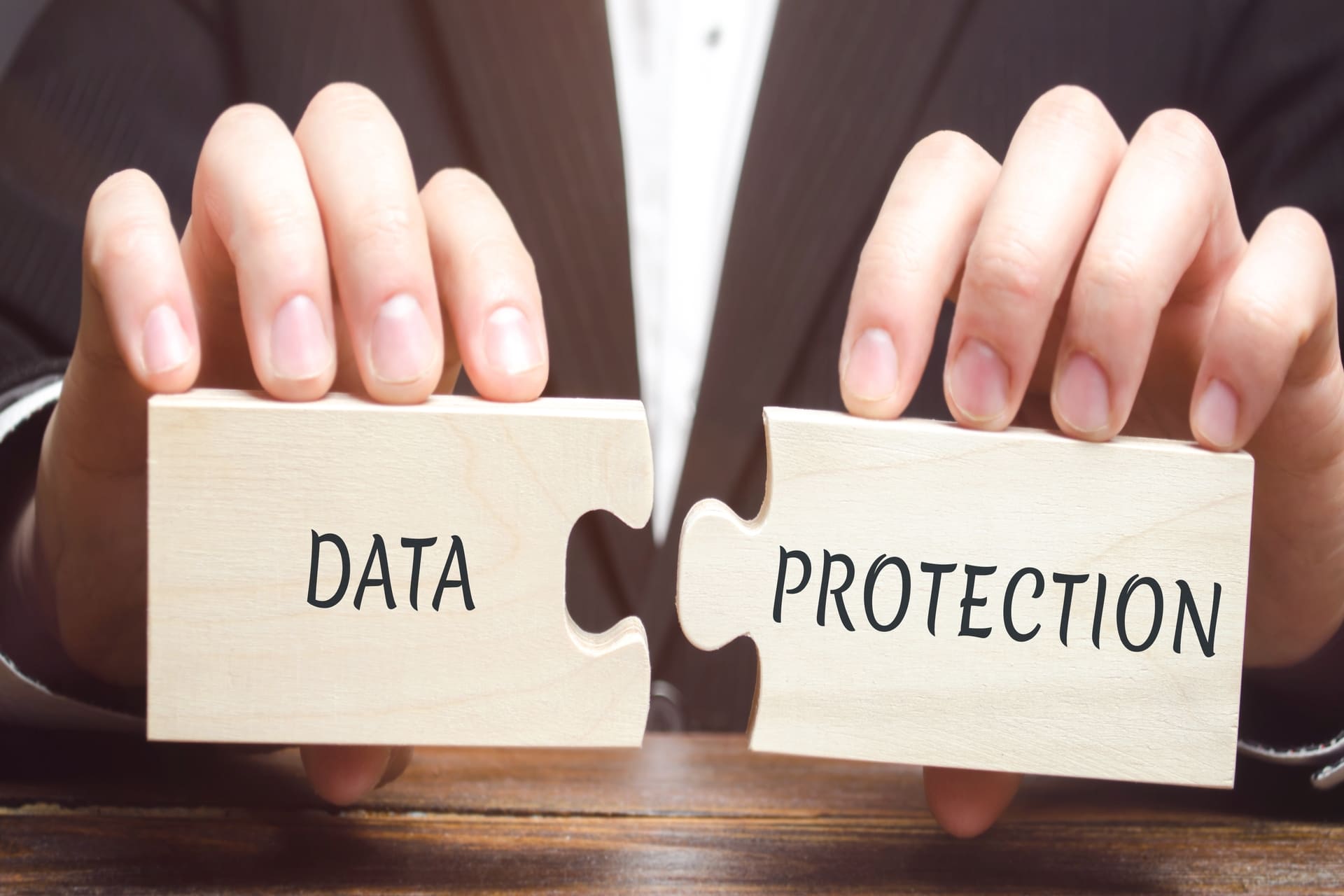 Businessman holding wooden puzzle pieces labeled data protection