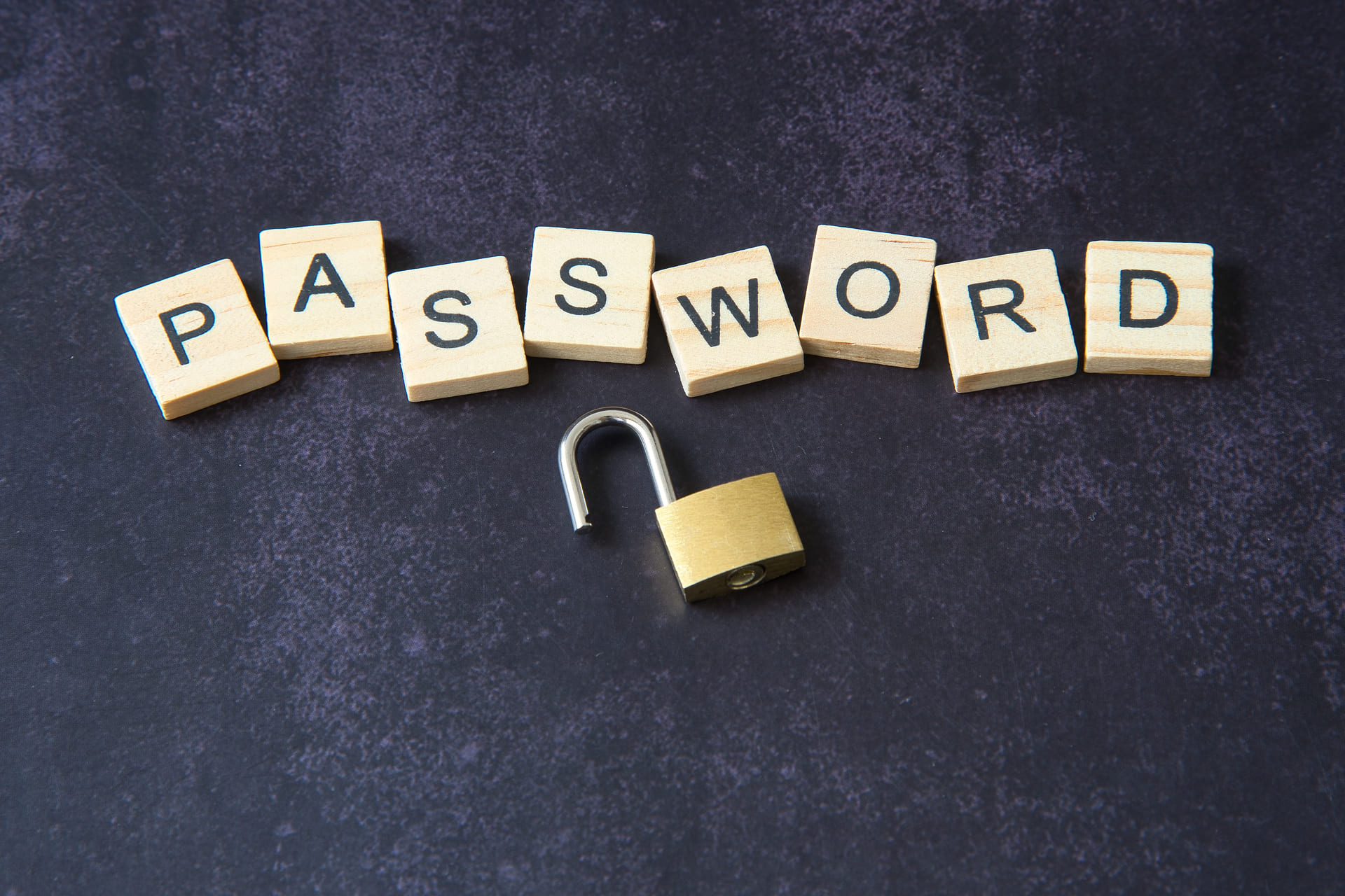 Password spelled with wooden tiles and open padlock on dark background
