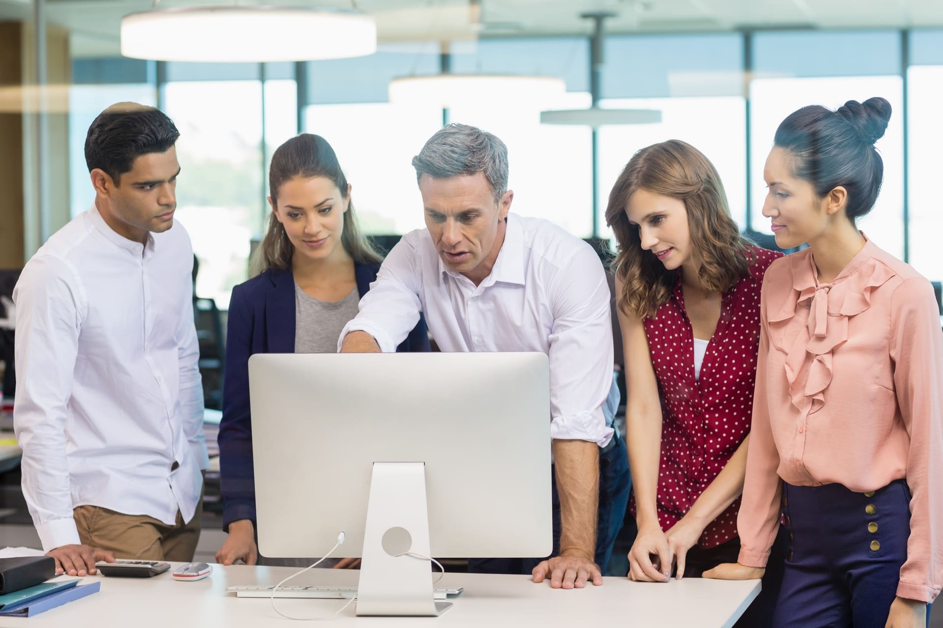 Team gathered around computer while leader explains project details