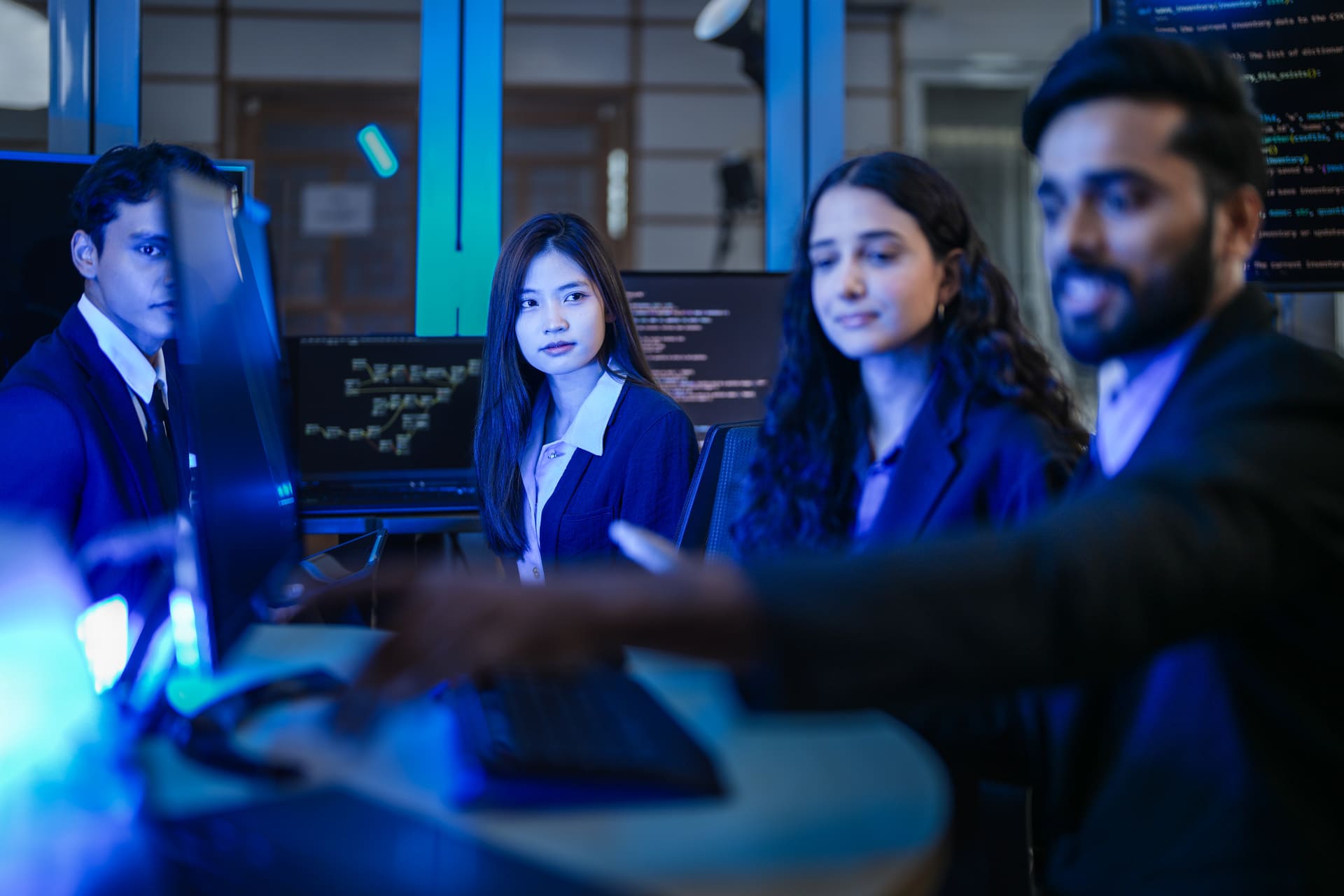 Team of IT professionals discussing work in a blue-lit office | CMIT Solutions Team of IT professionals discussing work in a blue-lit office