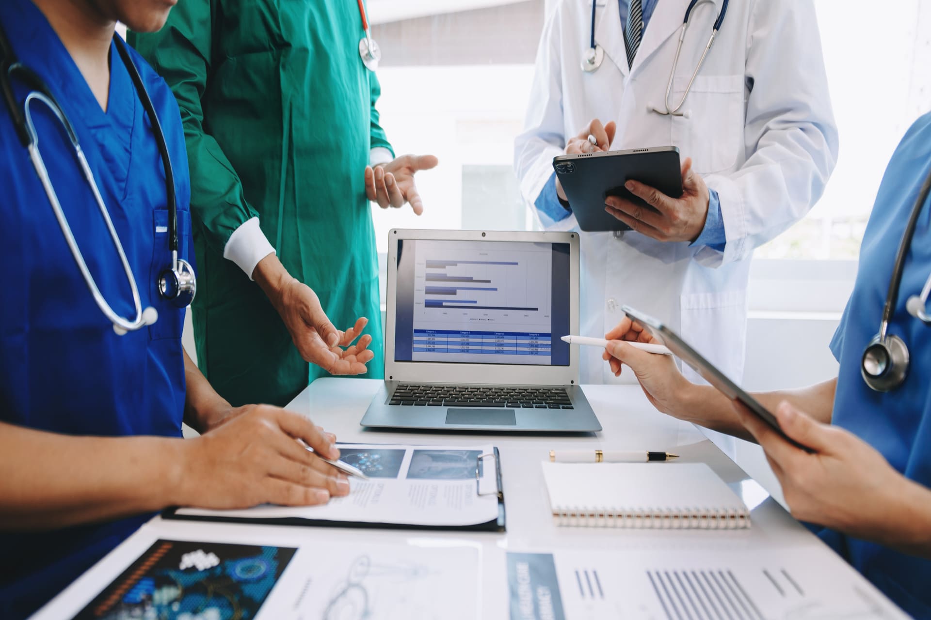 Doctors discussing patient data and charts during team meeting | CMIT Solutions Doctors discussing patient data and charts during team meeting