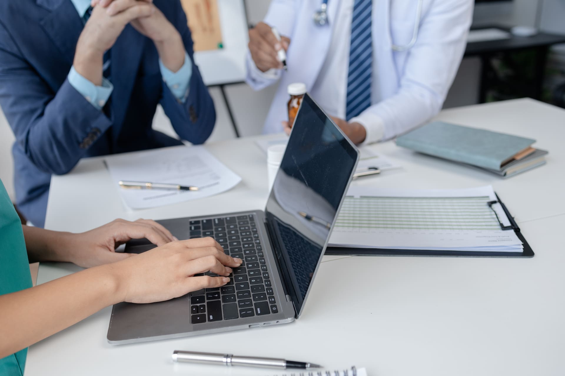 Medical team meeting with laptop and documents on table | CMIT Solutions Medical team meeting with laptop and documents on table