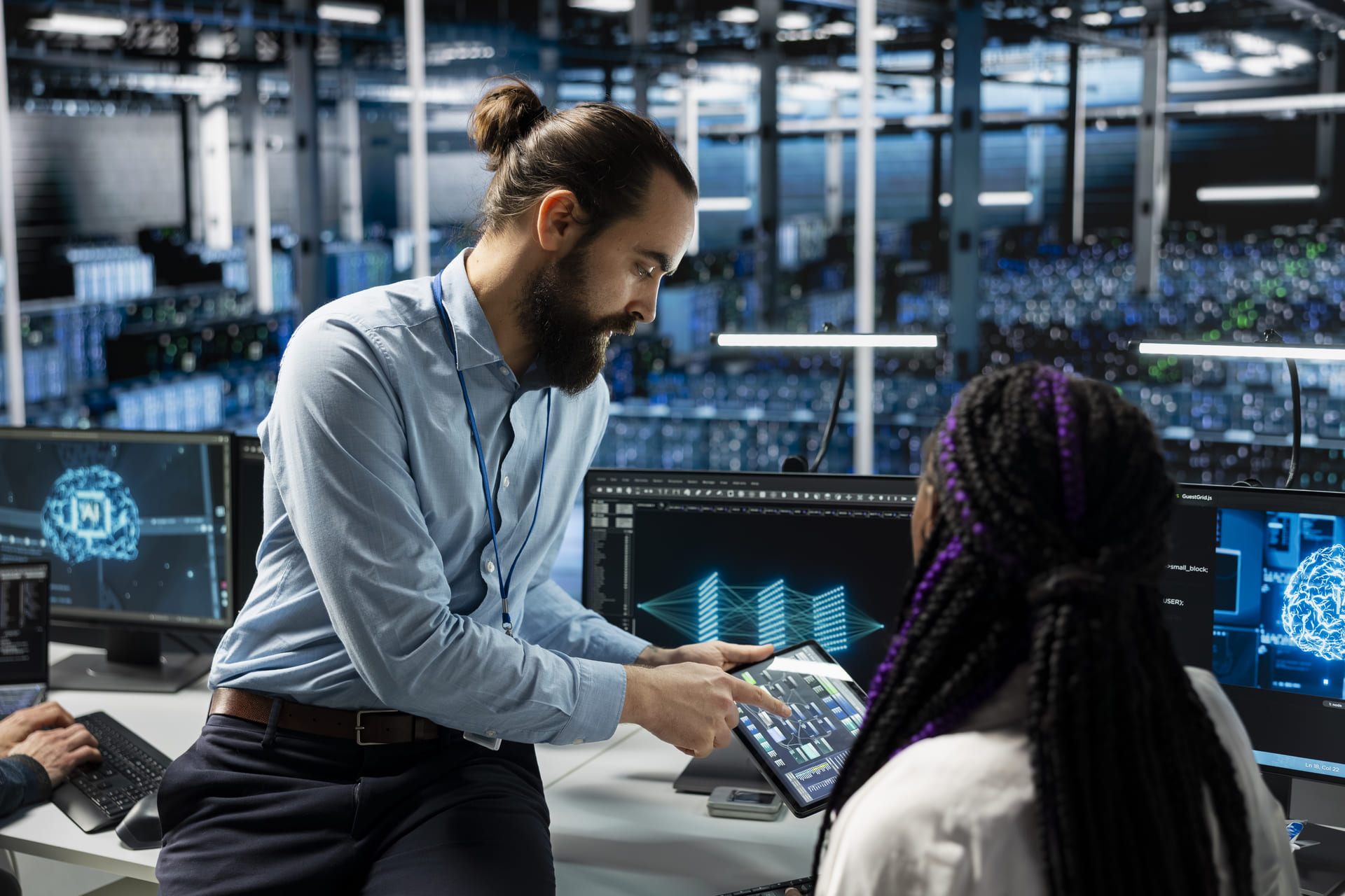 Team leader guiding intern while reviewing data on tablet in data center | CMIT Solutions Team leader guiding intern while reviewing data on tablet in data center - MDR Readiness