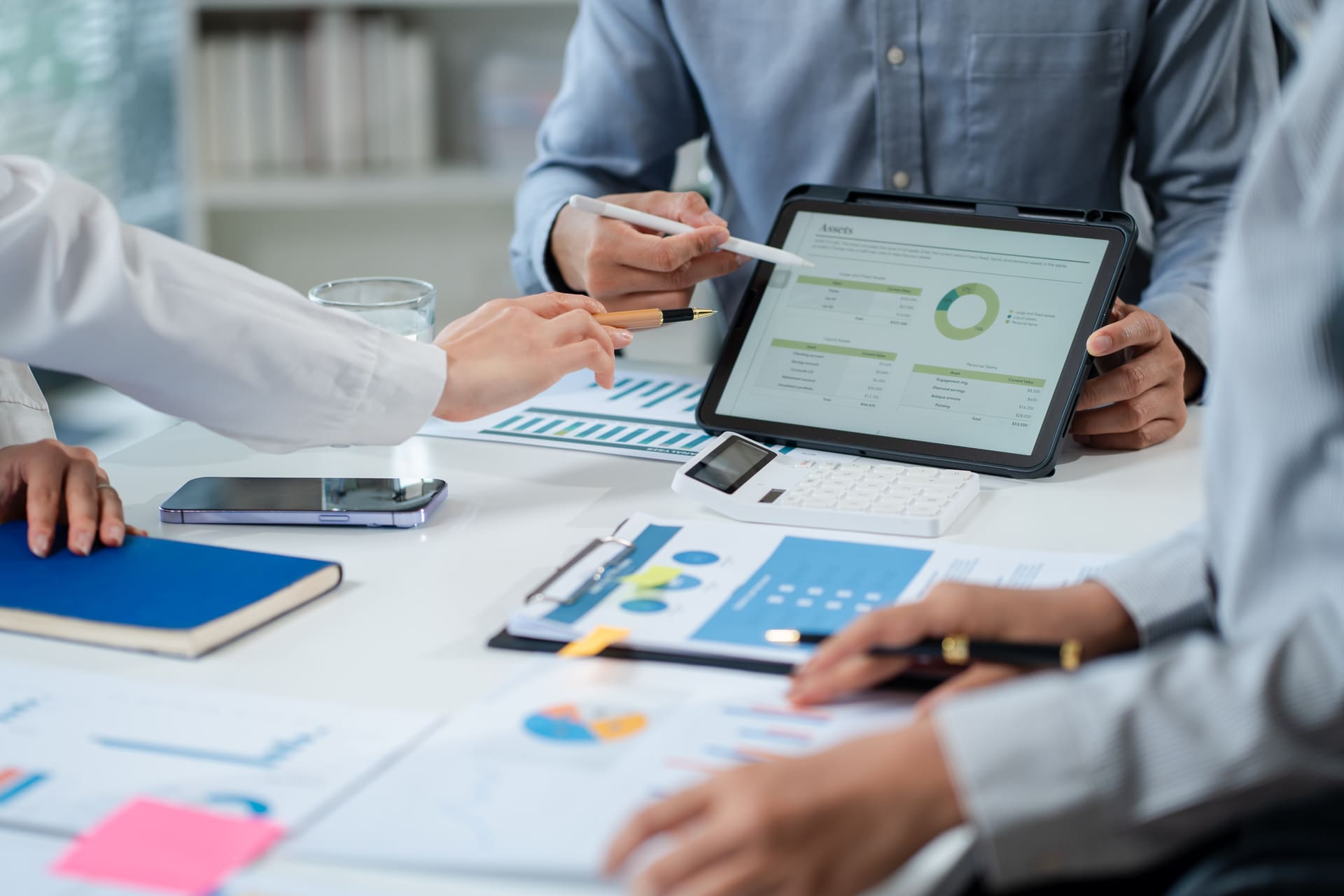 Colleagues pointing at financial data on a tablet during a collaborative discussion | CMIT Solutions Colleagues pointing at financial data on a tablet during a collaborative discussion