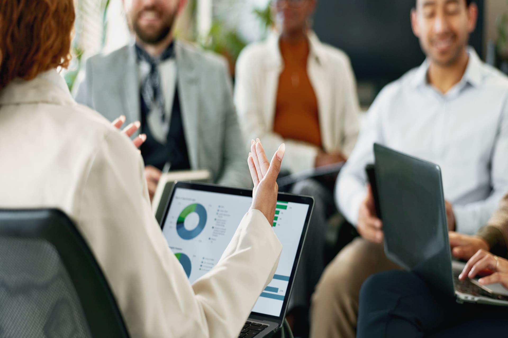 Team meeting with a person presenting data on a laptop to seated colleagues | CMIT Solutions Team meeting with a person presenting data on a laptop to seated colleagues