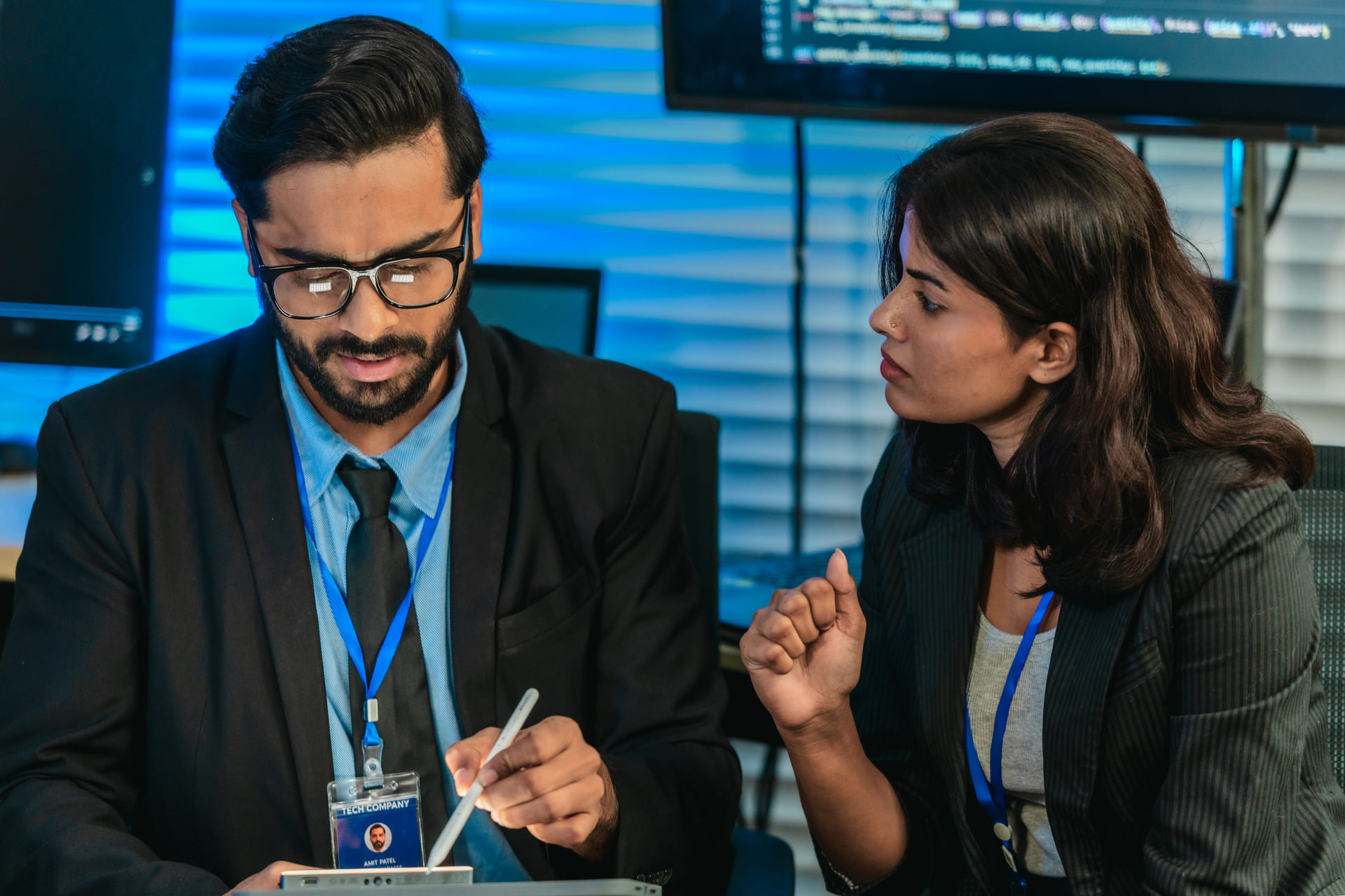 Two colleagues in discussion one using a stylus on a tablet while the other listens | CMIT Solutions Two colleagues in discussion one using a stylus on a tablet while the other listens