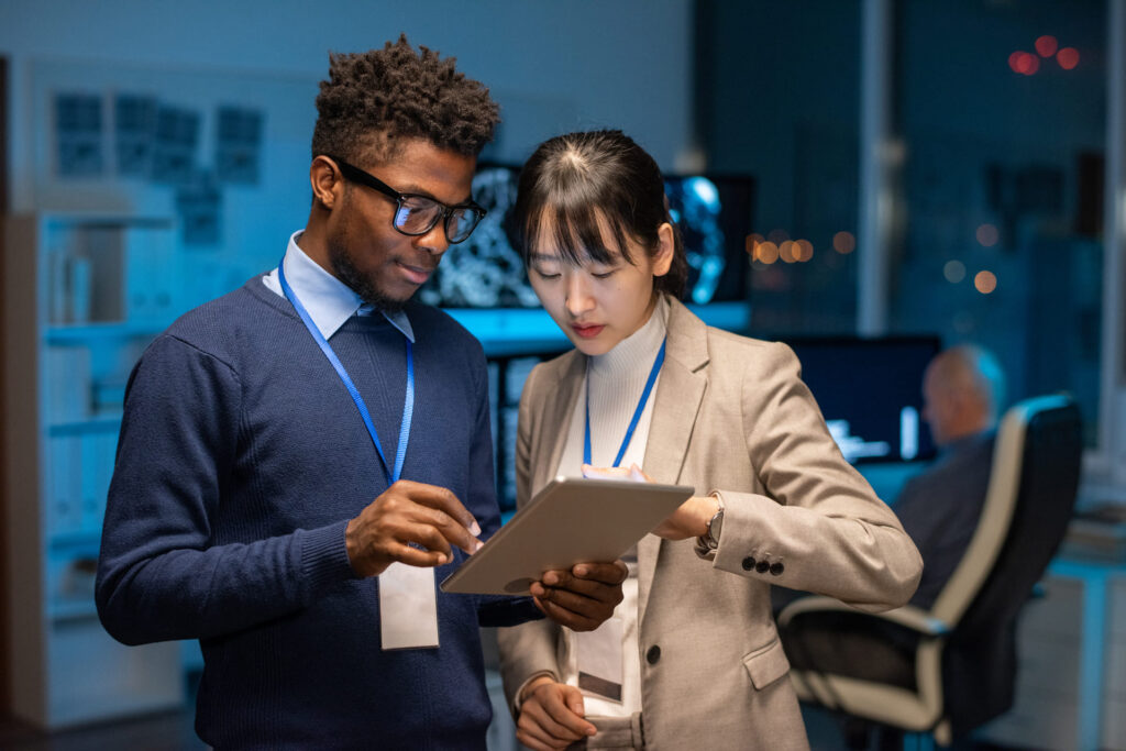 Two coworkers standing together reviewing information on a tablet in an office