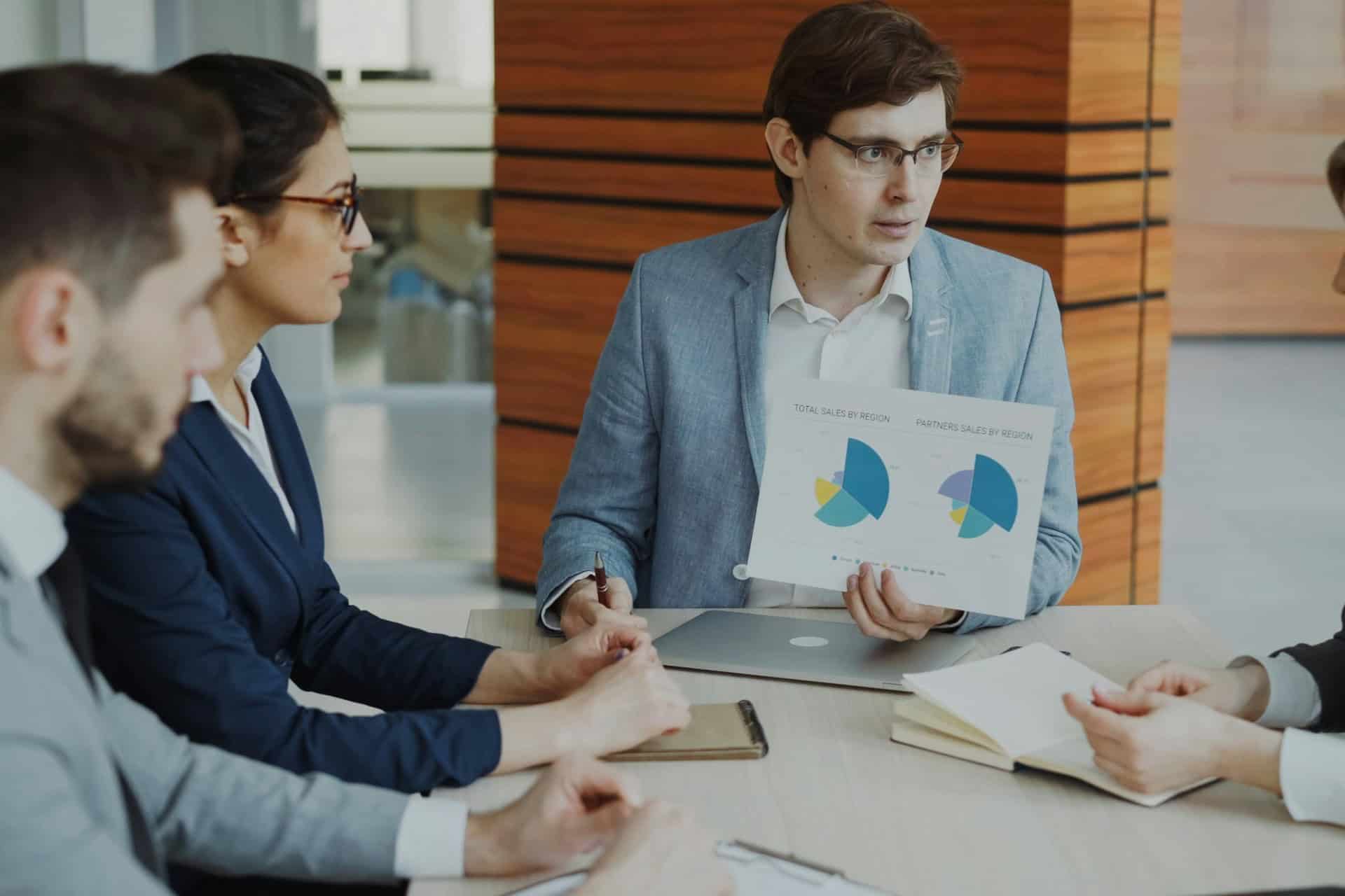 business-meeting-sales-analytics-report | CMIT Solutions Business professional presenting regional sales charts to colleagues during a meeting.