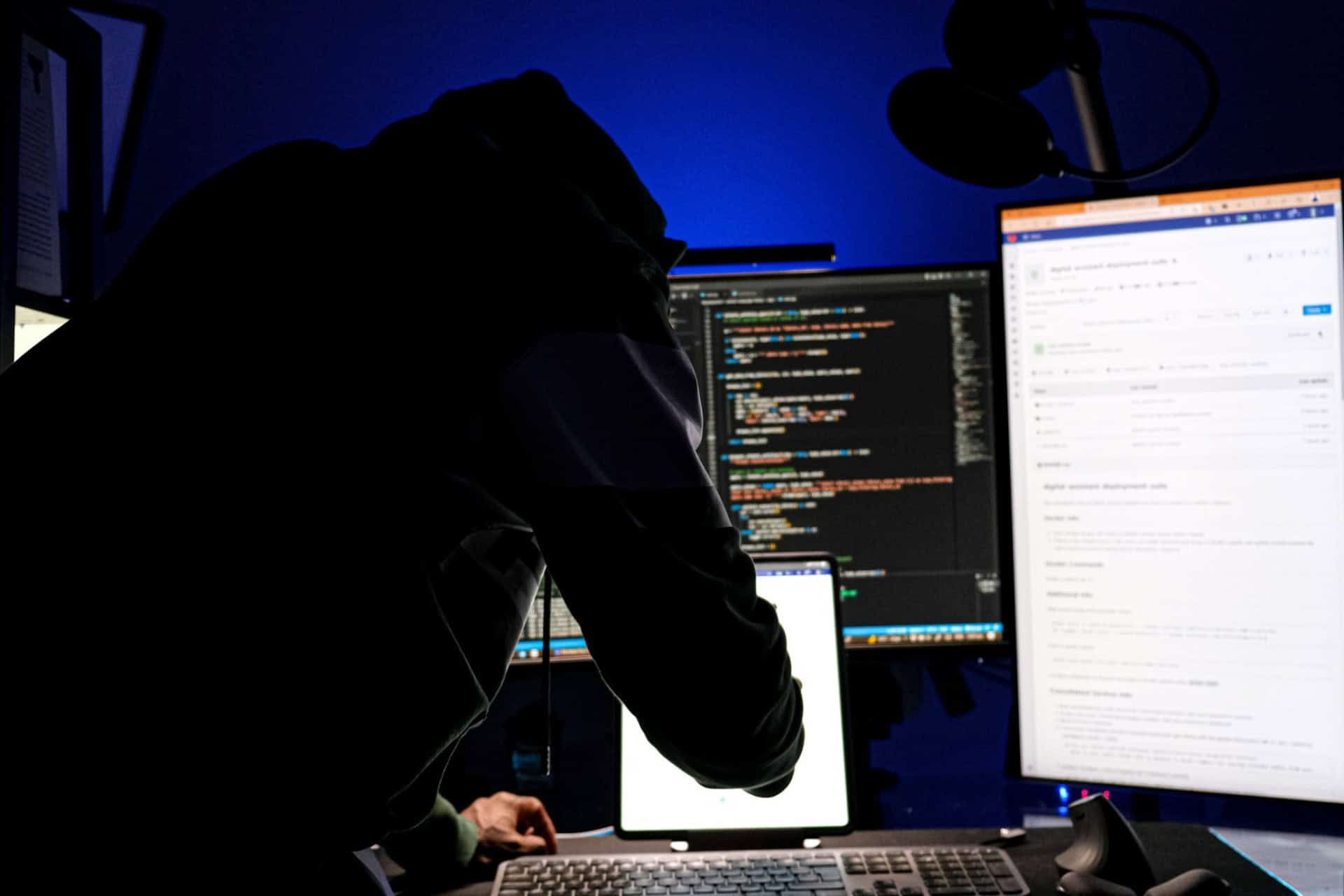 cybersecurity-developer-workstation-code | CMIT Solutions Developer working at a multi-monitor workstation displaying code in a dark blue-lit room.