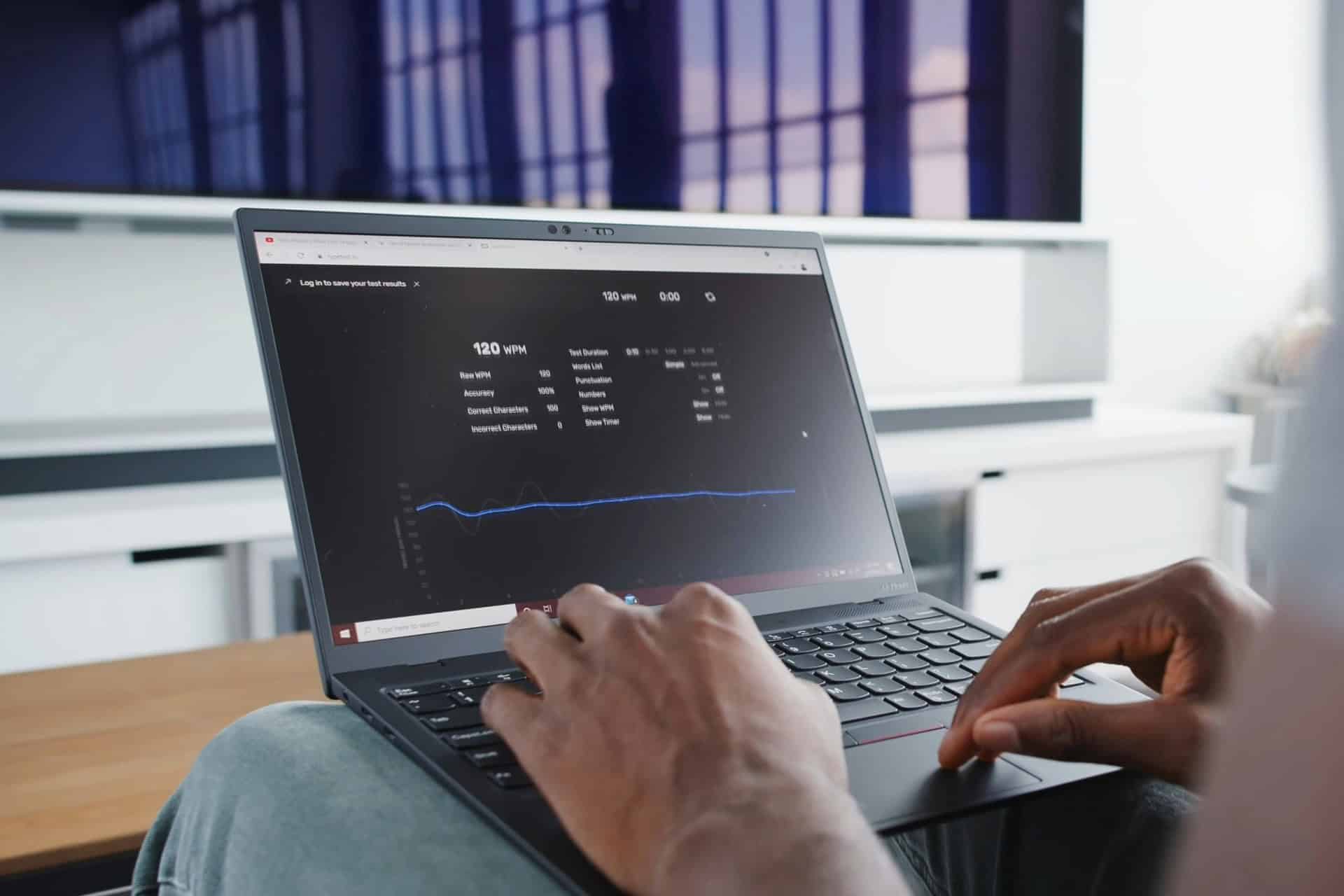laptop-typing-speed-test | CMIT Solutions Person using a laptop displaying typing speed test results with words-per-minute statistics and a performance graph.