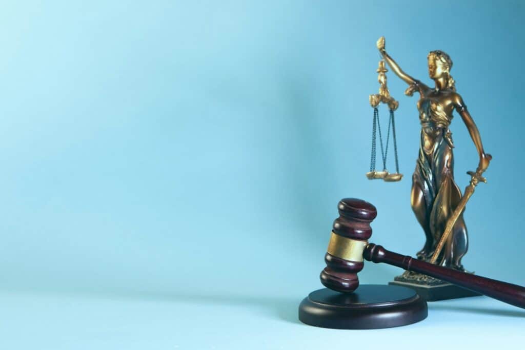 Bronze statue of Lady Justice holding the scales, with a gavel in the foreground.