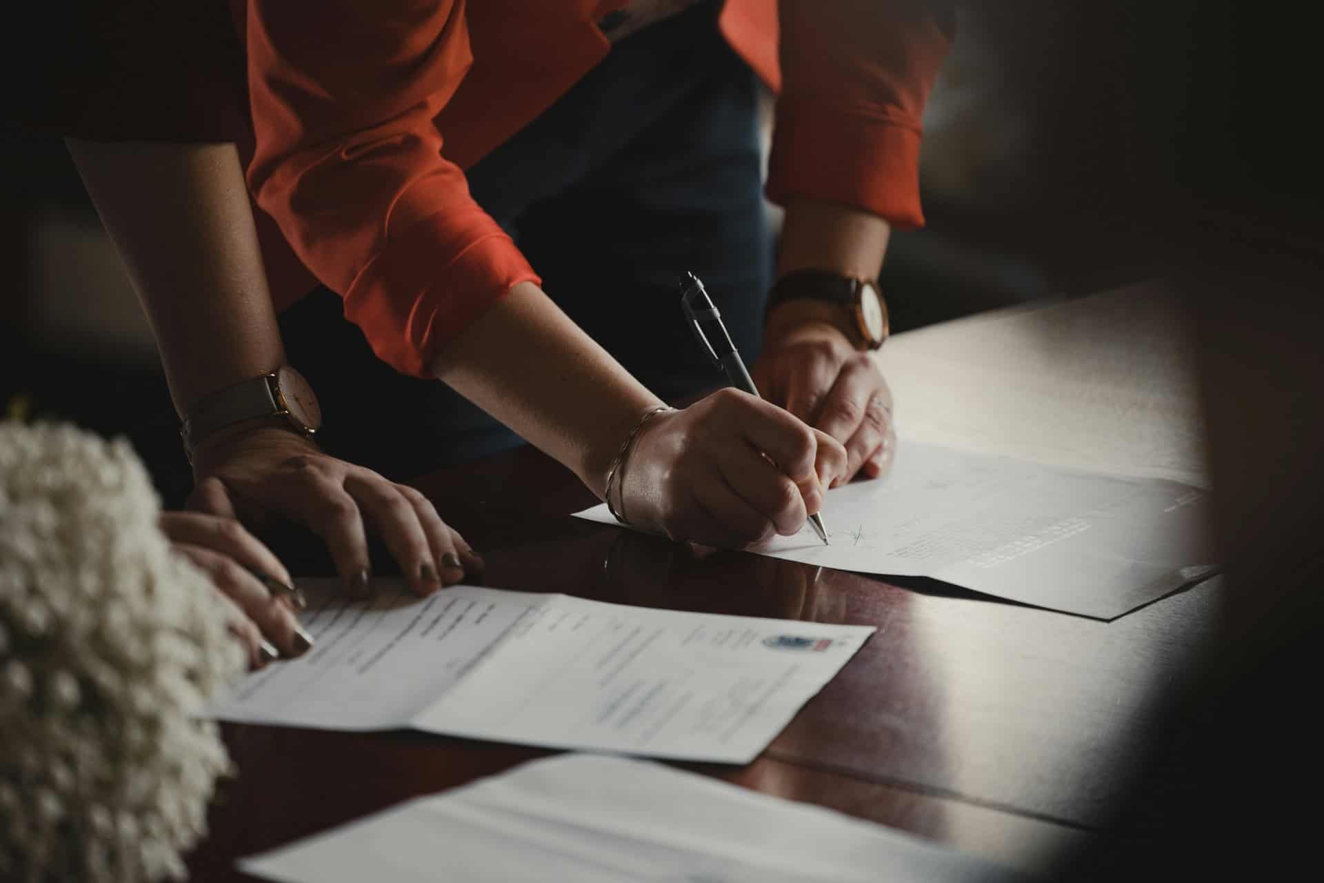 legal-document-signing | CMIT Solutions Person signing legal documents during a meeting at a desk.