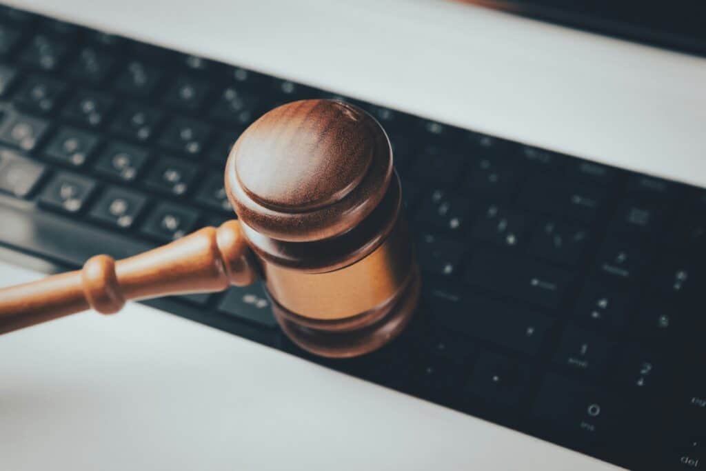 Wooden judge's gavel resting on a computer keyboard.
