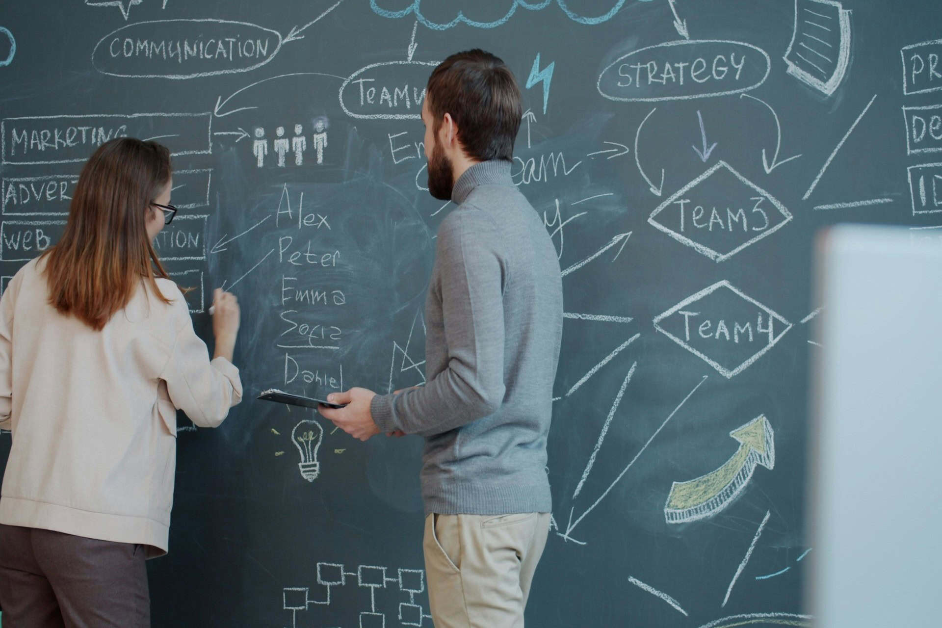 vitaly-gariev-ski1gz3c0W0-unsplash 1 | CMIT Solutions Two colleagues plan a marketing and team strategy using diagrams on a chalkboard.