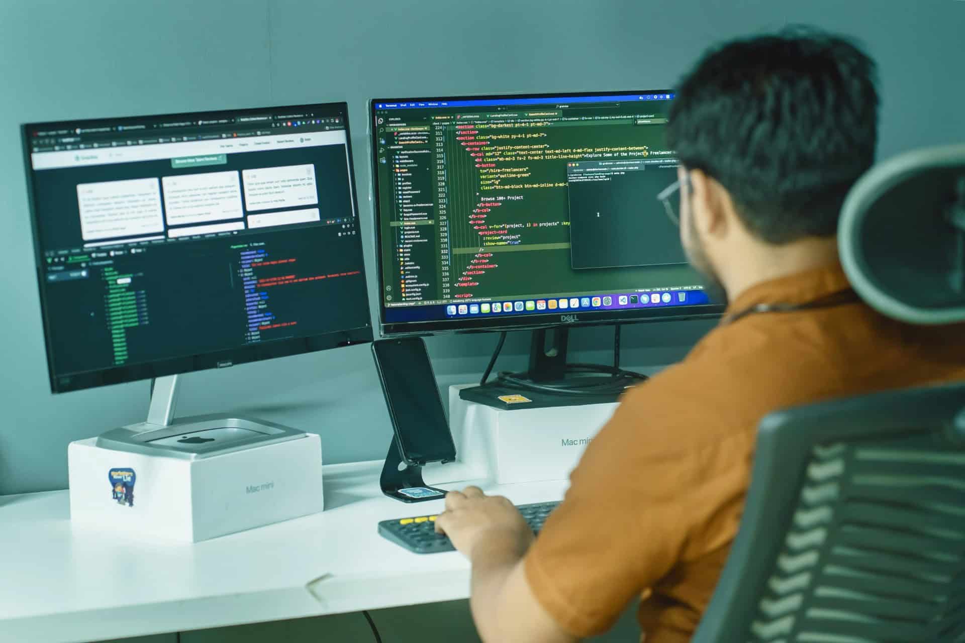 web-developer-dual-monitor-coding | CMIT Solutions Web developer working at a desk with two monitors displaying programming code and a development interface.